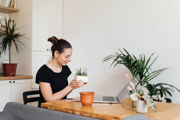 Jong duizendjarige vrouw die vanuit huis werkte. Kamer met planten. Freelancer bloemist — Stockfoto