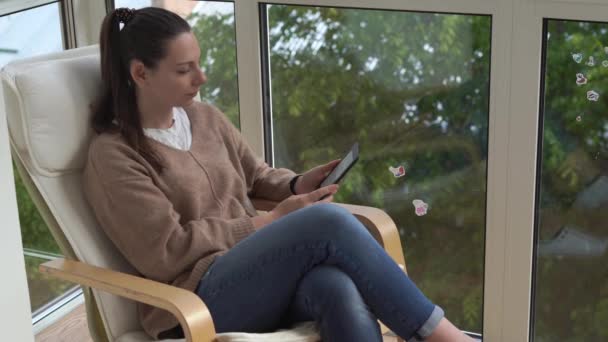 YOung mulher lendo e-book na varanda. Covid-19 de quarentena hobby em casa — Vídeo de Stock