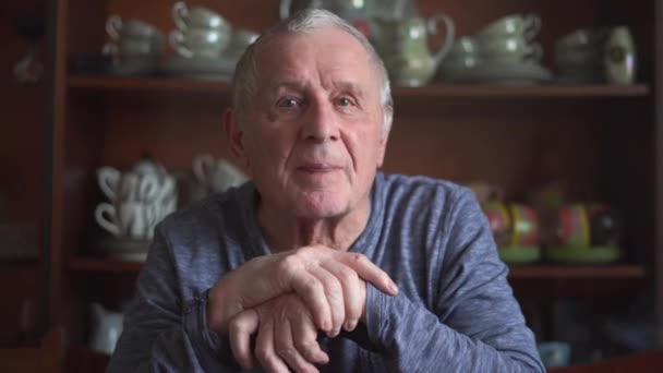 Oudere man in de 80 zit en thuis met stok en praat met de camera — Stockvideo