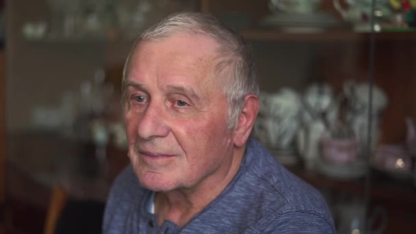 Пожилой человек 80 лет сидит и разговаривает с камерой — стоковое видео