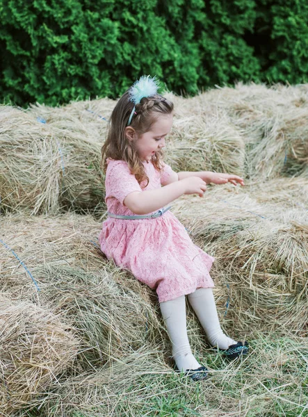 Pequeña niña se juega en el heno —  Fotos de Stock