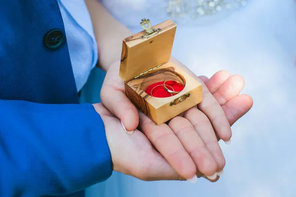 Anelli nuziali in una scatola di legno, mani in luna di miele — Foto Stock