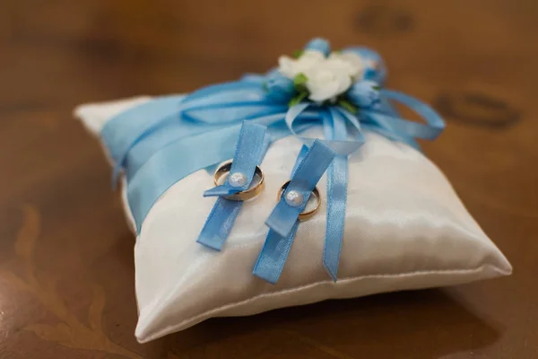 Wedding rings on a pillow with a blue ribbon — Stock Photo, Image