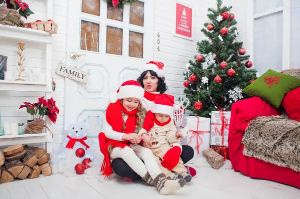 크리스마스 트리 근처 가족의 크리스마스 파티. 그녀의 딸과 아들 젊은 어머니. — 스톡 사진
