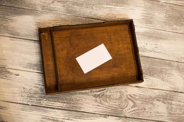 Scatola di legno scuro con carta bianca. Fondo in legno chiaro. Spazio per testo . — Foto Stock