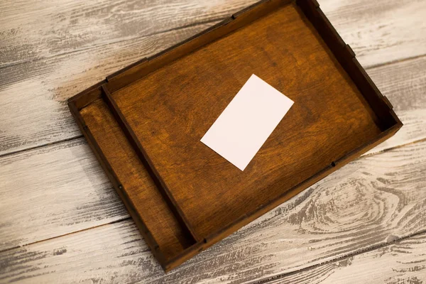 Scatola di legno scuro con carta bianca. Fondo in legno chiaro. Spazio per testo . — Foto Stock