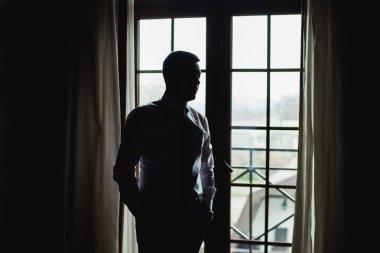 Erkek avukat silüeti zor bir günden sonra aittir ama özel bir ofis pencerenin yanında duruyor. Kopya alanı reklam içerik için