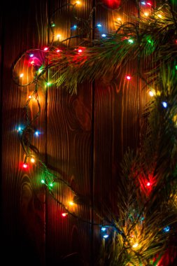 Çelenk ve çelenk renkli ışık ampuller. Noel ışıkları ve serbest metin alanı arka plan. Noel ışıkları sınır. Ahşap arka plan üzerinde renkli Noel ışıkları parlayan. Yeni yıl.