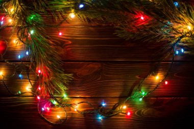 Çelenk ve çelenk renkli ışık ampuller. Noel ışıkları ve serbest metin alanı arka plan. Noel ışıkları sınır. Ahşap arka plan üzerinde renkli Noel ışıkları parlayan. Yeni yıl.