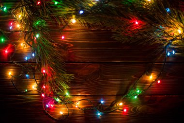 Çelenk ve çelenk renkli ışık ampuller. Noel ışıkları ve serbest metin alanı arka plan. Noel ışıkları sınır. Ahşap arka plan üzerinde renkli Noel ışıkları parlayan. Yeni yıl.