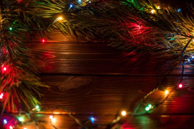 Çelenk ve çelenk renkli ışık ampuller. Noel ışıkları ve serbest metin alanı arka plan. Noel ışıkları sınır. Ahşap arka plan üzerinde renkli Noel ışıkları parlayan. Yeni yıl.
