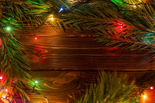 Çelenk ve çelenk renkli ışık ampuller. Noel ışıkları ve serbest metin alanı arka plan. Noel ışıkları sınır. Ahşap arka plan üzerinde renkli Noel ışıkları parlayan. Yeni yıl.
