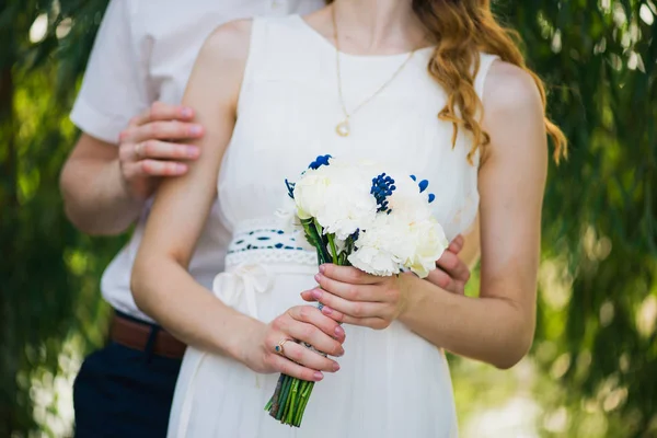 Mani di sposa e sposo con anelli sul bouquet da sposa. Concetto di matrimonio. — Foto Stock