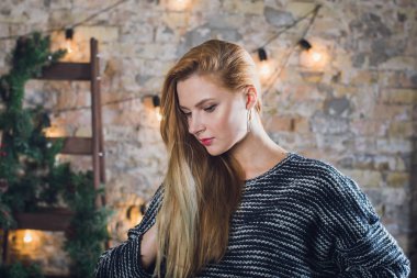 Kadın modeli ve tuğla taş. Güzel kız, uzun kızıl saçlı. Bir merdiven, bir tuğla duvar önünde duran bir kadın