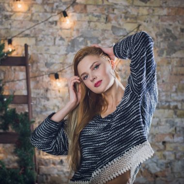 Kadın modeli ve tuğla taş. Güzel kız, uzun kızıl saçlı. Bir merdiven, bir tuğla duvar önünde duran bir kadın