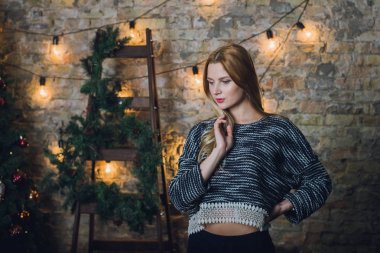 Kadın modeli ve tuğla taş. Güzel kız, uzun kızıl saçlı. Bir merdiven, bir tuğla duvar önünde duran bir kadın