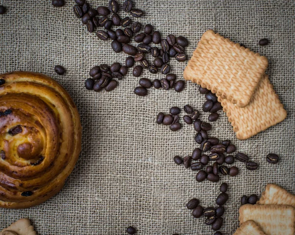 Pão doce com passas em um saco de malha com grãos de café e biscoitos — Fotografia de Stock