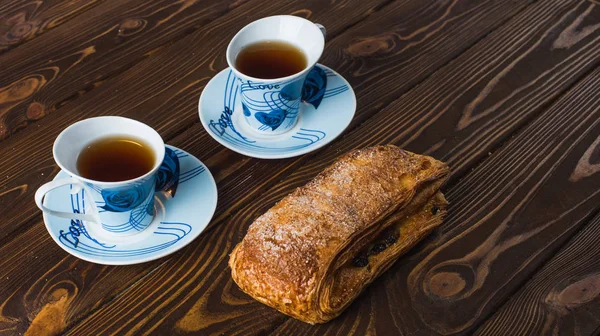 ขนมปังพัฟกับถ้วยชาบนพื้นหลังไม้ . — ภาพถ่ายสต็อก