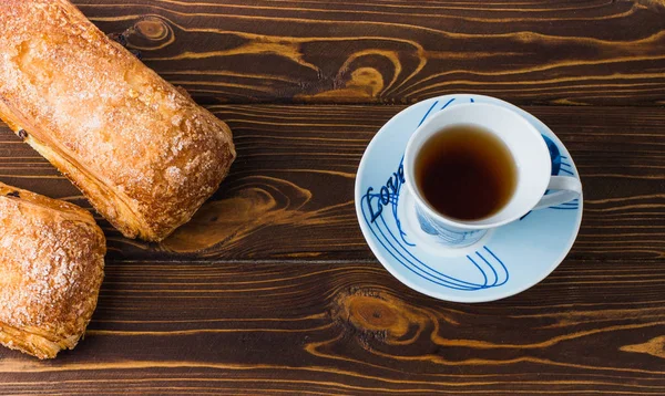 Blätterteig mit einer Tasse Tee auf einem hölzernen Hintergrund. — Stockfoto