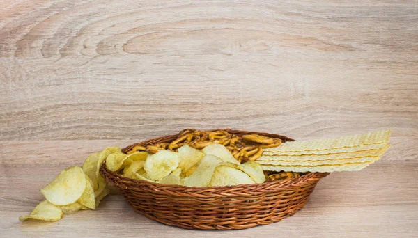 Chips and cracker on a wooden background. Plate with chips. — Stock Photo, Image