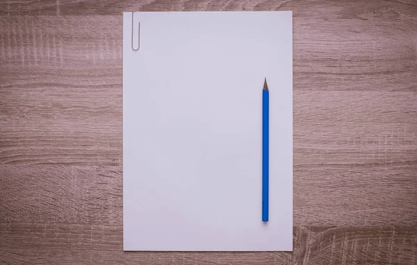 Carta bianca bianca bianca con una matita su un tavolo di legno . — Foto Stock