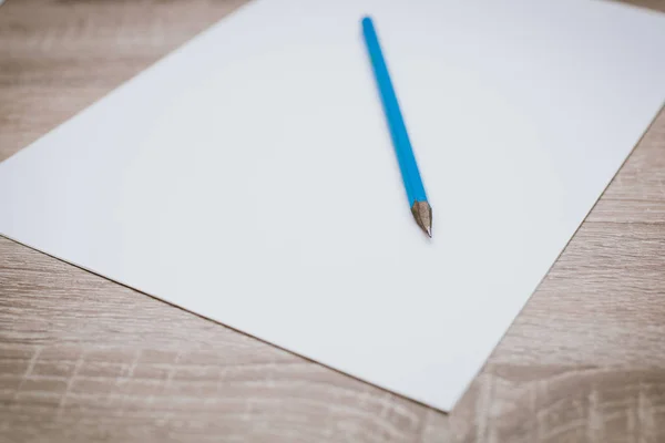 Carta bianca bianca bianca con una matita su un tavolo di legno . — Foto Stock