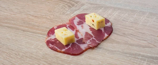 Two slices of cheese with meat on a wooden background — Stock Photo, Image