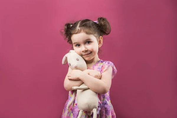 Concepto de la infancia, juguetes y personas - linda niña abrazando una liebre de peluche —  Fotos de Stock