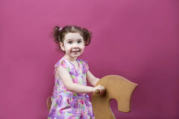Niña sentada en un caballo de juguete —  Fotos de Stock