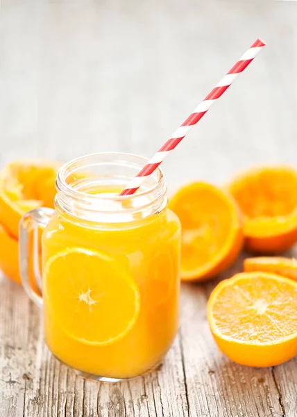 Suco de laranja espremido em frasco de vidro com fundo rústico — Fotografia de Stock