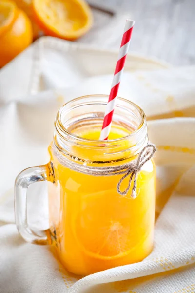 Kruik glas met SAP en stro met resten van geperste oranje — Stockfoto