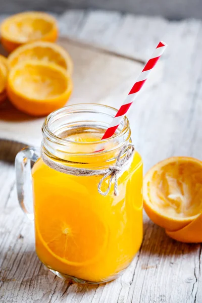 Γυάλινο βάζο στο προσκήνιο με χυμό πορτοκαλιού — Φωτογραφία Αρχείου