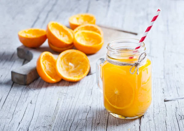 Glass jar in the foreground with orange juice — Stock Photo, Image
