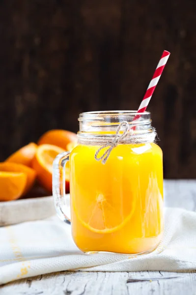 Frasco de vidro em primeiro plano com suco de laranja — Fotografia de Stock