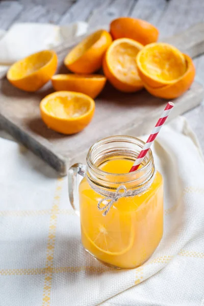 Γυάλινο βάζο στο προσκήνιο με χυμό πορτοκαλιού — Φωτογραφία Αρχείου