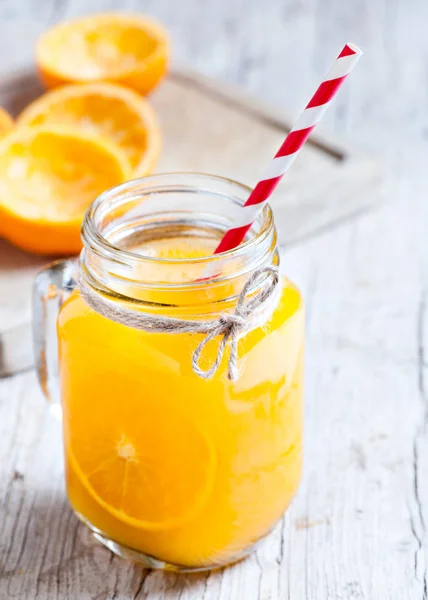 Delicious orange juice squeezed in the foreground in glass ja — Stock Photo, Image
