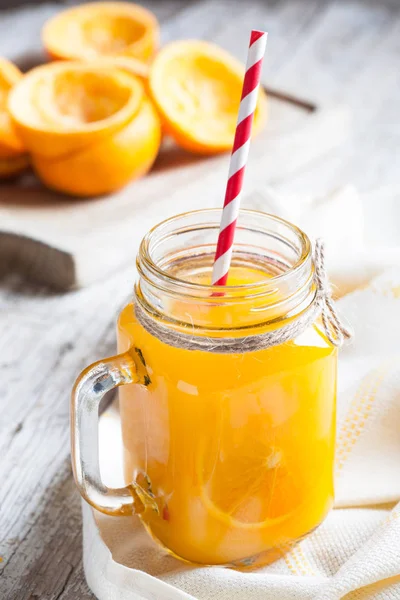 Delicious orange juice squeezed in the foreground in glass ja — Stock Photo, Image