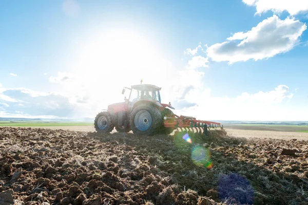 Traktor i landområden tillsammans med redskap för arbete — Stockfoto