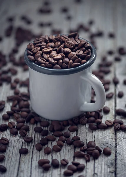 Kopp i porslin med kaffebönor i förgrunden i vintage styl — Stockfoto