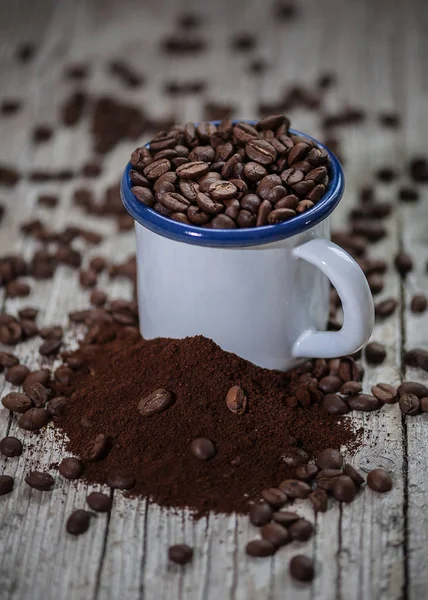 Чашка порцеляни з кавовими зернами на передньому плані в вінтажному стилі — стокове фото