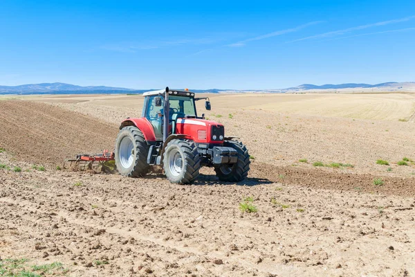 Landbrukstraktor i forgrunnen med blå himmel i ryggen – stockfoto