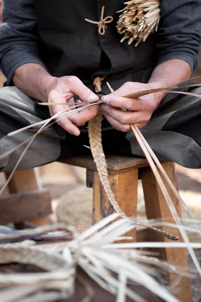 old wicker craftsman with hands working in isolated foregroun