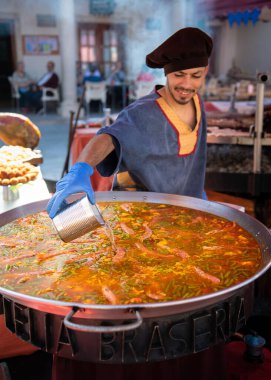 Deniz ürünleri paella 'sı ve yanında da aşçı var.