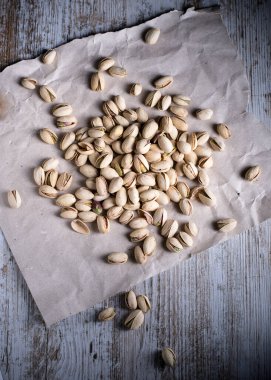 karanlık backgroun ile ön planda ahşap masa üzerinde antep fıstığı