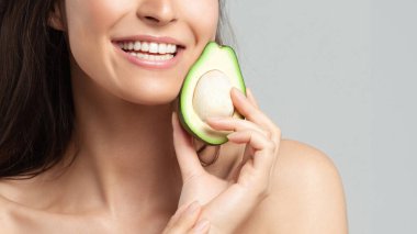 Avokado tutan genç ve güzel bir kadın. Güzellik, gençlik, cilt bakımı