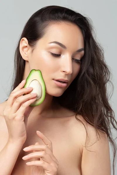 Avokado tutan genç ve güzel bir kadın. Güzellik, gençlik, cilt bakımı