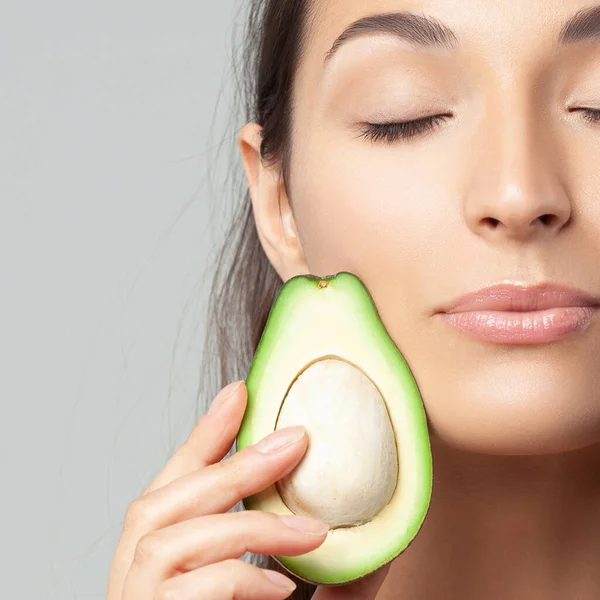 Avokado tutan genç ve güzel bir kadın. Güzellik, gençlik, cilt bakımı
