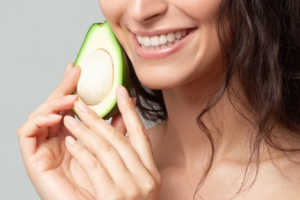 Avokado tutan genç ve güzel bir kadın. Güzellik, gençlik, cilt bakımı