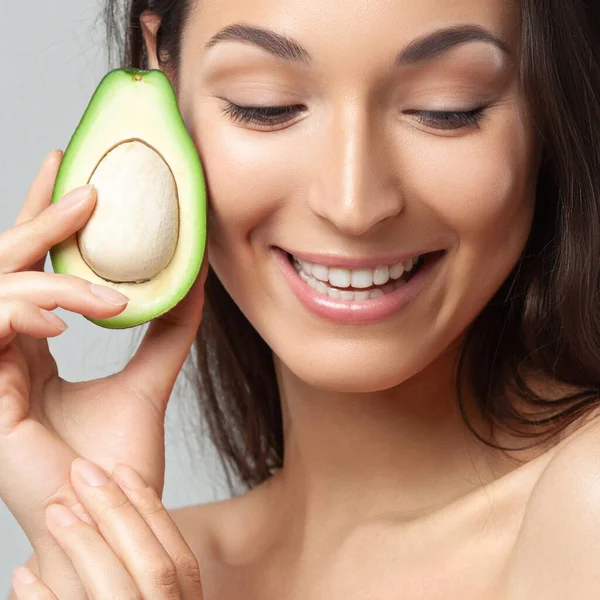 Avokado tutan genç ve güzel bir kadın. Güzellik, gençlik, cilt bakımı