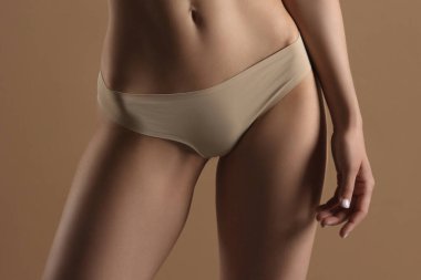 Bej arka planda iç çamaşırlı zayıf bir genç kadın. Spor, diyet, cilt ve vücut bakımı